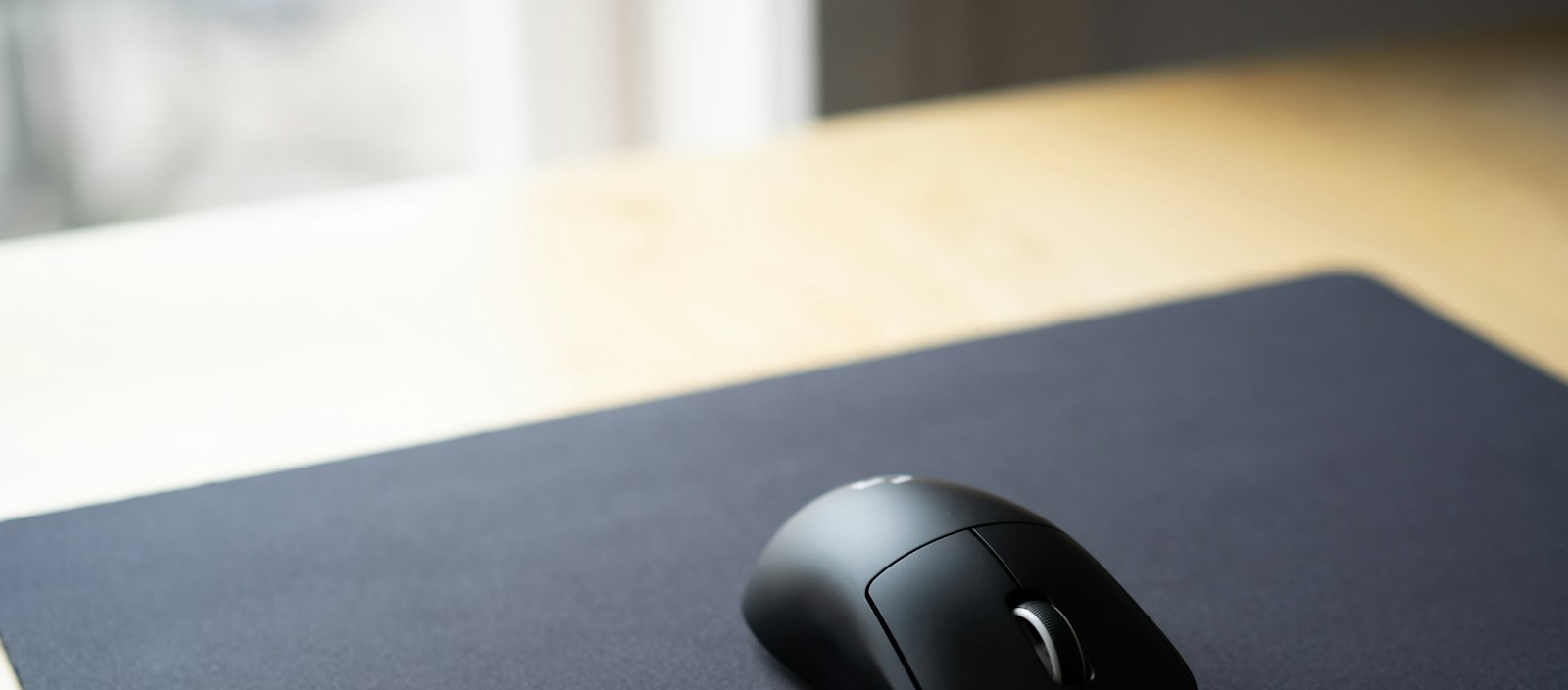 Close-up of a matte-black wireless mouse on a desk mat